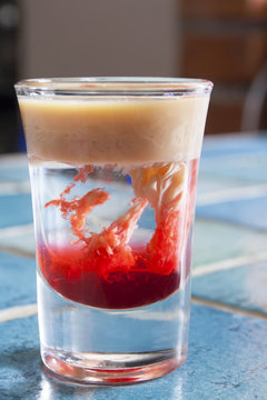 Monkey-brain cocktail in a shot glass on blue tiled bar - table.