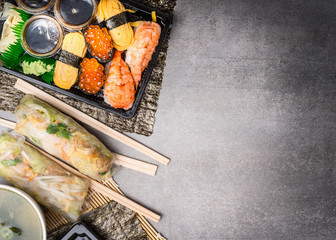 Sushi menu with summer rolls, nigiri and soy sauce on gray stone  background, top view, place for text, border