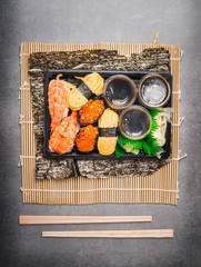Sushi menu with rolls and nigiri in plastic transport box with chopsticks, top view