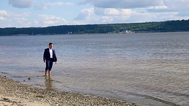 Businessman having rest walking on the beach after a hard day. HD.