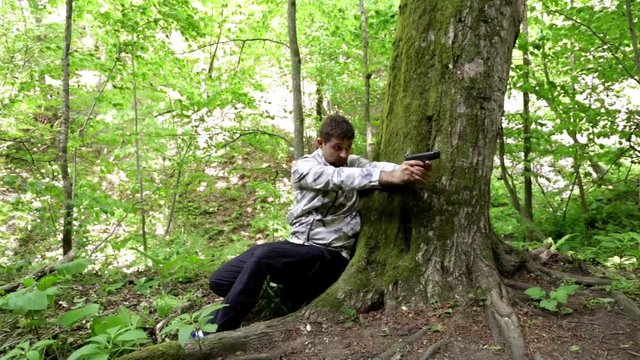 Man shoots a gun in the forest. zombie apocalypse. shoot from the enemies. shoot to kill. to fire a gun. to defend against enemies. sniper. self-defense. away from the chase. shooting training.