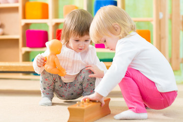 Pensive kids playing in kindergarten room