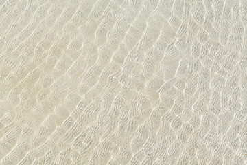 transparent water ripple and sunlight glare on white sand
