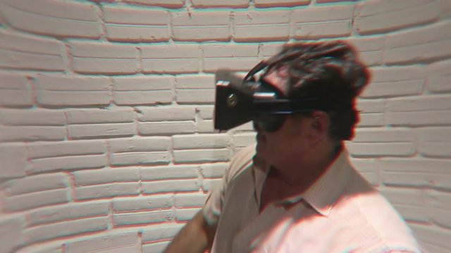 Man wearing virtual reality VR headset glasses dances with an imaginary partner during an emotional simulated virtual adventure gaming session - he then goes fishing and reels in a big one. 