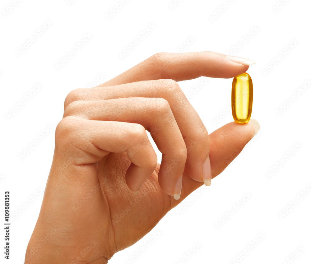 Wall mural Woman's hand holding Omega 3 capsule isolated on white background. Close up. High resolution product.