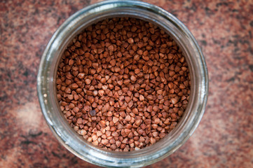 The glass container with buckwheat on the kitchen table