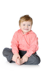 Adorable little boy smiling, sitting on the floor, studio shot, isolated on white background
