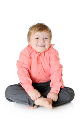 Adorable little boy smiling, sitting on the floor, studio shot,