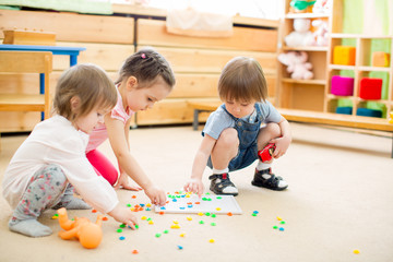 kids playing mosaic game in kindergarten room 