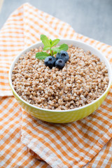 Buckwheat porridge in a bowl with mint leaves and blueberries.