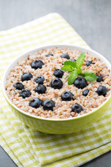 Buckwheat porridge in a bowl with mint leaves and blueberries.
