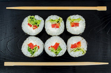 Sushi on a black wooden tray with chopsticks 
