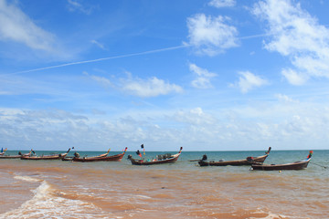 line of arrange fishing boat with rope at beach harbor island in sunny blue sky