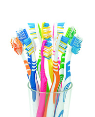 Десять разноцветных зубных щеток в стеклянном стакане на изолированном белом фоне