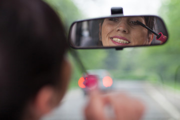Fototapeta na wymiar applying mascara while driving a car