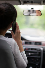 young woman driving and using cell phone