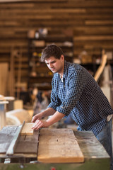 Skilled carpenter working in his woodwork workshop, using a circ