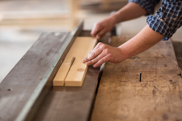 Skilled carpenter working in his woodwork workshop, using a circ