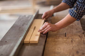 Skilled carpenter working in his woodwork workshop, using a circ