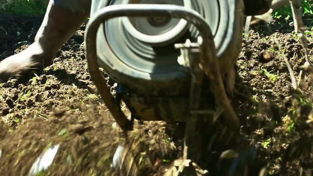 Farmer using machine mart cultivator for ploughing soil 