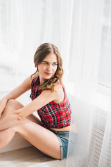 Fototapeta premium merry curly girl sitting in light room at window lifestyle