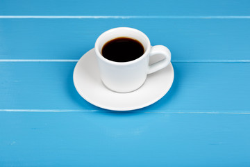 Cup of black drink on blue wooden background.