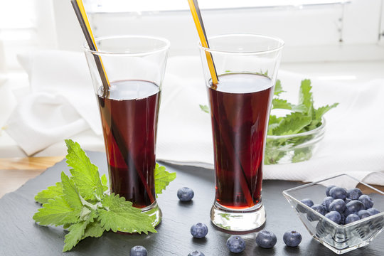 Glasses with fresh Black Currant juice. Bog blueberry and lemon balm