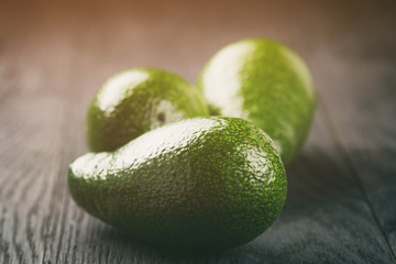 ripe green avocados on wood table, vintage toned