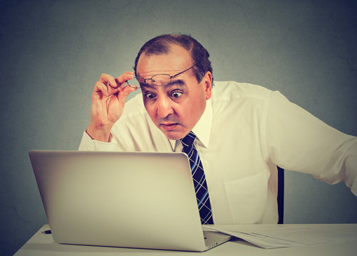 Portrait of a shocked man reading message on computer in office