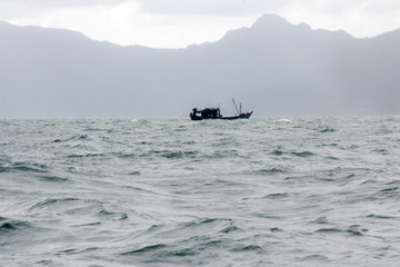 Thai fishing boats in the sea on a background of mountains