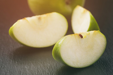 ripe green apples sliced on slate board, vintage toned