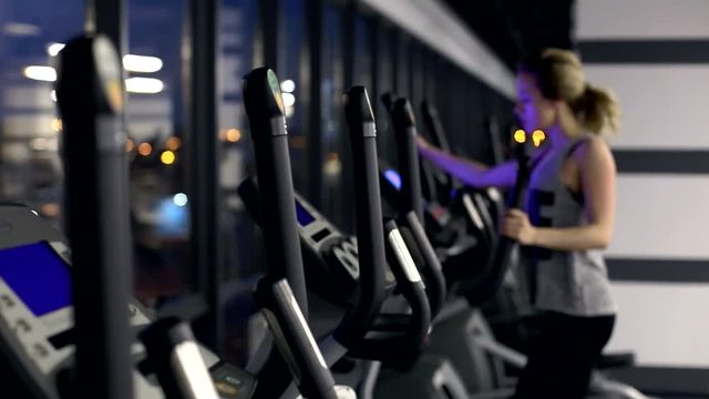 view of emty gym with one girl on elliptical trainer. She wants to be better