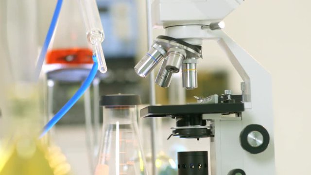 Movement tracks down from a distillation kit to a microscope and other lab paraphernalia.
