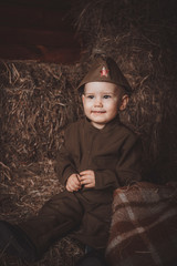 Retro! One year smiling baby dressed in Second World War russian uniform.  Hay background