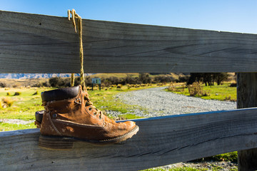 Old hiking shoes hanging on a wooden fence