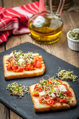 Grilled toasted bread with roasted tomatoes, feta cheese and radish sprouts.