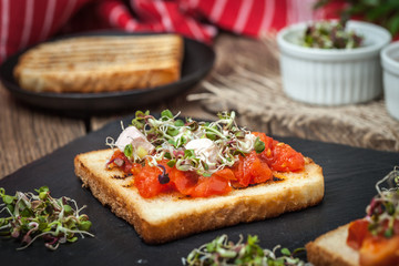 Grilled toasted bread with roasted tomatoes, feta cheese and radish sprouts.