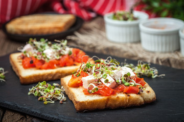 Grilled toasted bread with roasted tomatoes, feta cheese and radish sprouts.