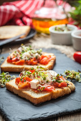 Grilled toasted bread with roasted tomatoes, feta cheese and radish sprouts.