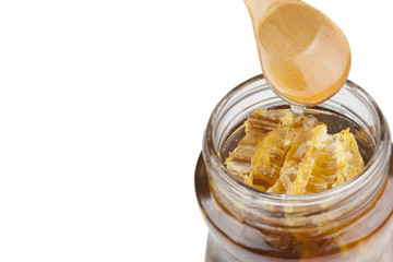 Jar of honey with wooden drizzler on white background