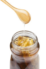 Jar of honey with wooden drizzler on white background