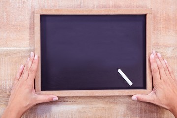 Composite image of hand holding a chalkboard