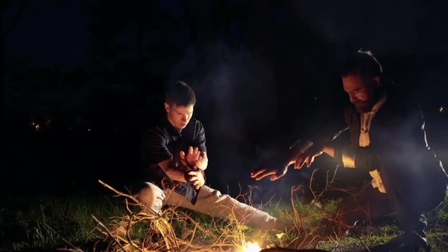 Two men doing moves over bonfire on thr night. 4K