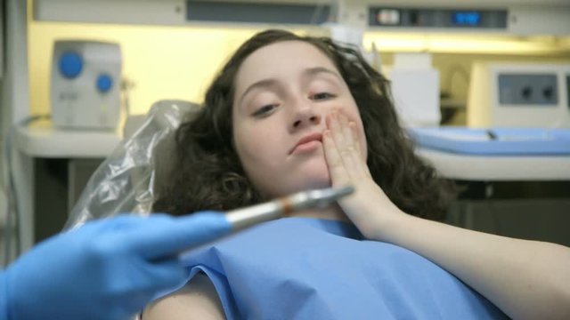 The Camera Does A Rack Focus From A Dental Drill To A Cute Teenage Patient Who Appears Anxious At The Sight Of It.