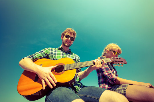 Young man hipster playing guitar for woman.