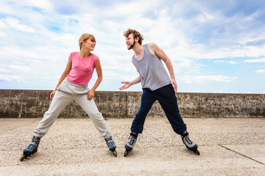 Two people exercise stretch outdoor on rollerblades.