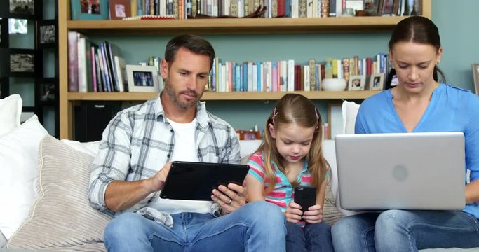 Two parents with her daughter using technologies