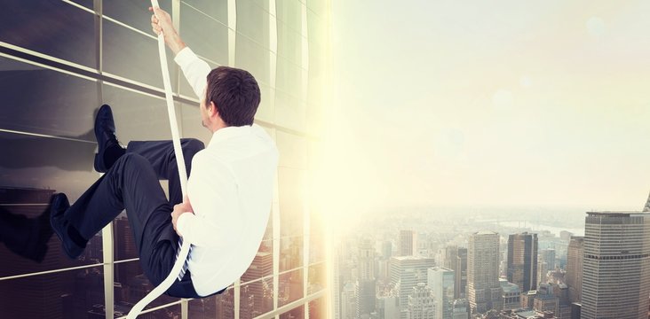 Composite image of businessman pulling a rope with effort