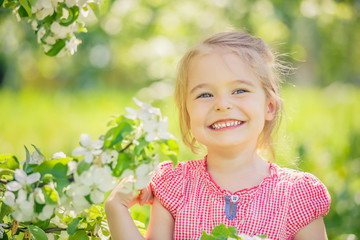 Happy little girl playing in spring apple tree garden