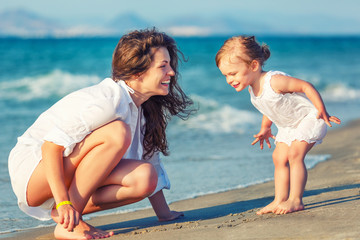 Mother and little daughter playing on the beach